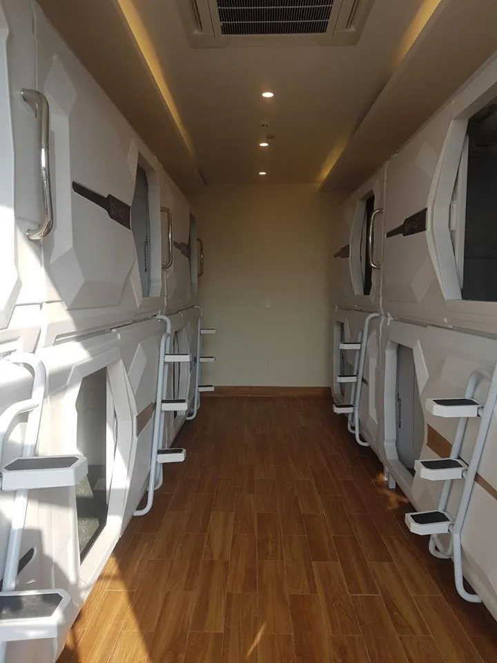 Real capsule hotel aisle with two-tier pod doors, ladders and ceiling lights