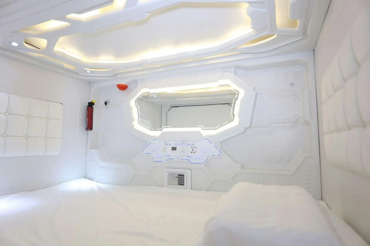 Real white capsule bed interior with fitted linen, lights, wall surfaces and a control panel