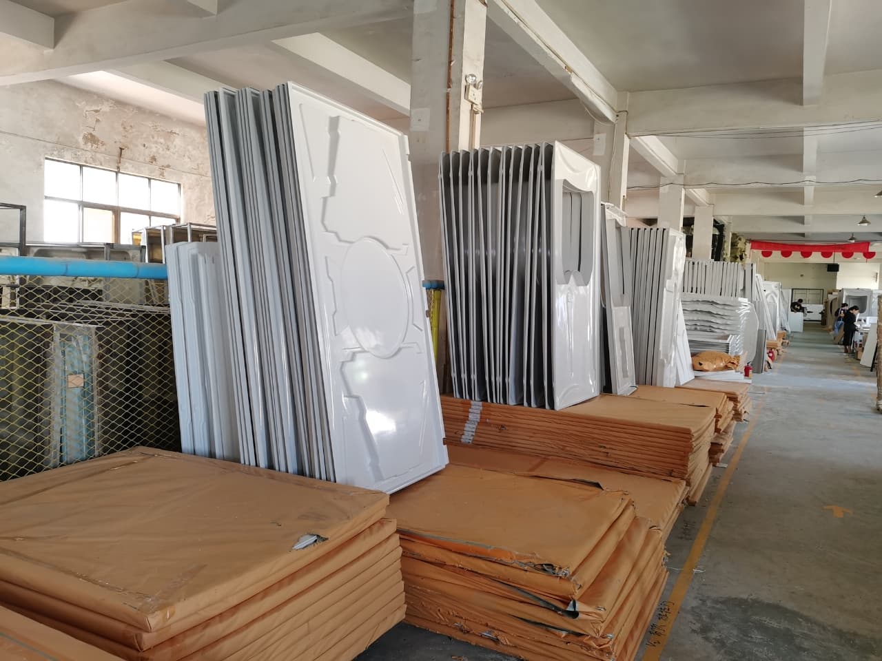 Organized stacks of white capsule shell panels and protected flat components in the workshop